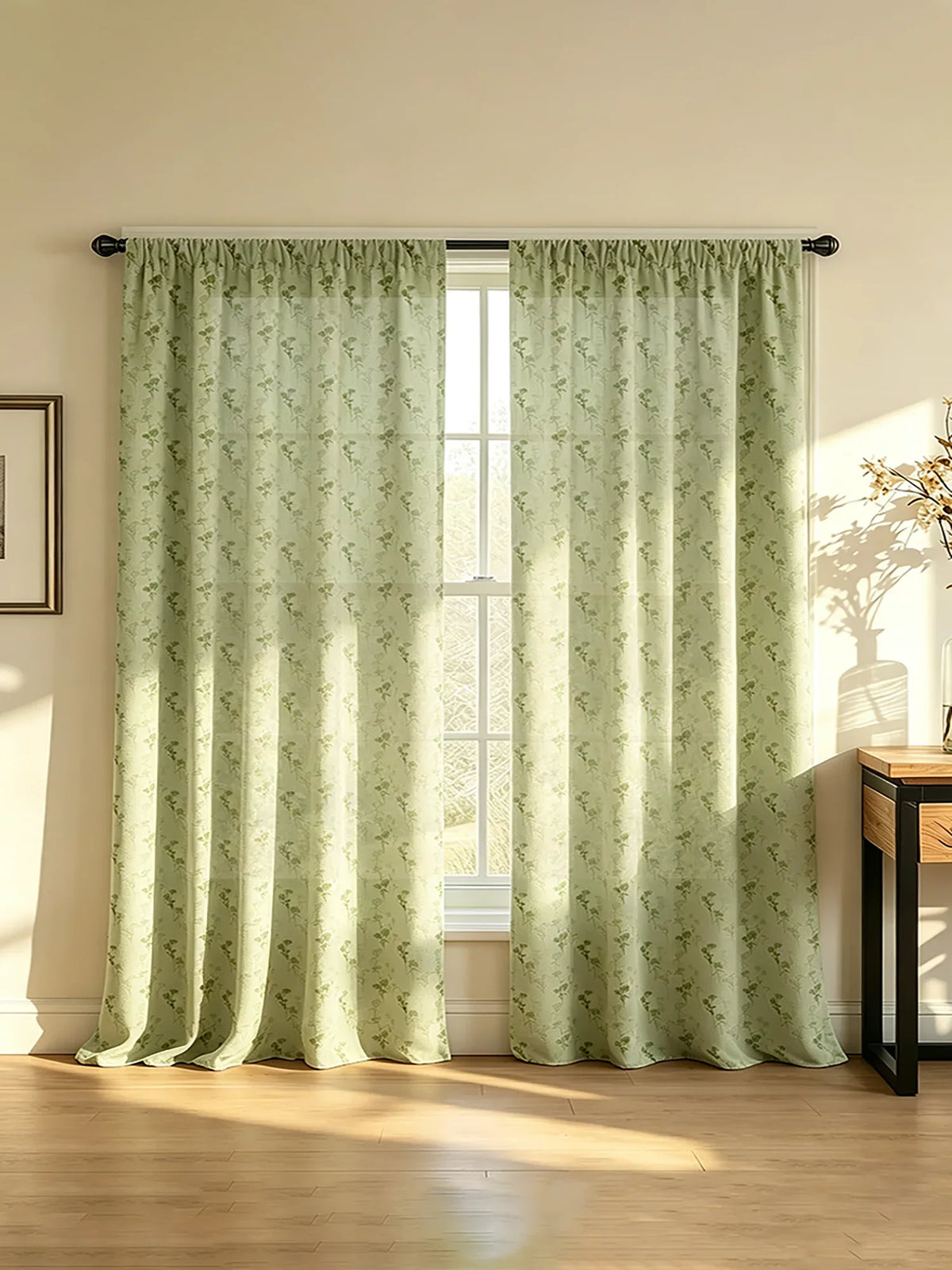 A pair of light green floral print curtains hanging in a window, filtering soft sunlight onto a wooden floor.