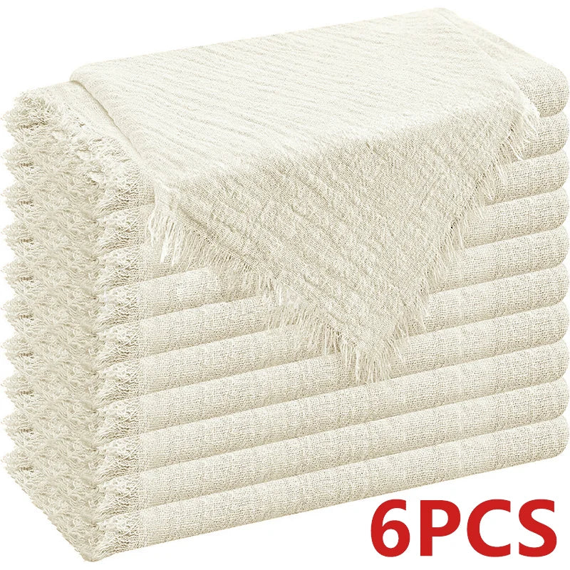 A stack of six beige textured cloth napkins with fringed edges.