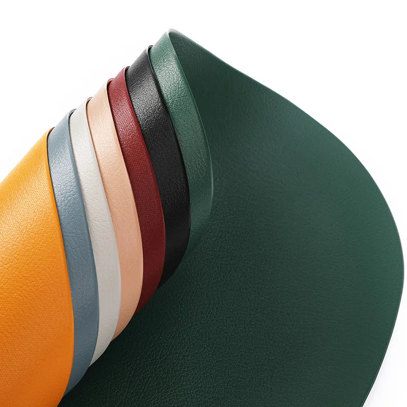 A stack of colorful reusable vinyl placemats in various shades of green, brown, orange, and beige.