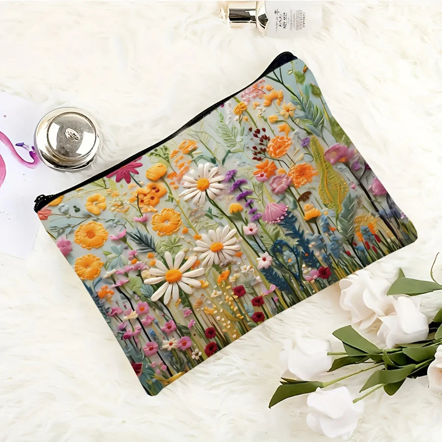 A floral canvas cosmetic bag with a zipper closure featuring colorful wildflowers and greenery on a white fluffy surface.