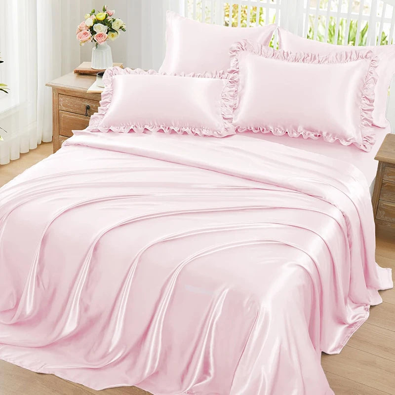 A set of two pink ruffled satin pillowcases with silky envelope closures displayed on a bed.