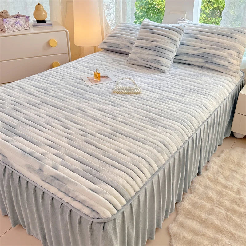 A plush bed skirt linen set featuring light blue and white striped bedding on a bed with a white nightstand.