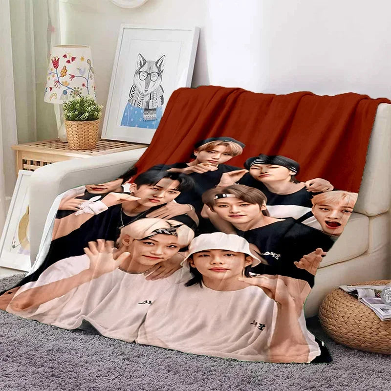 A group of male Kpop idols are printed on a large orange fleece throw blanket.