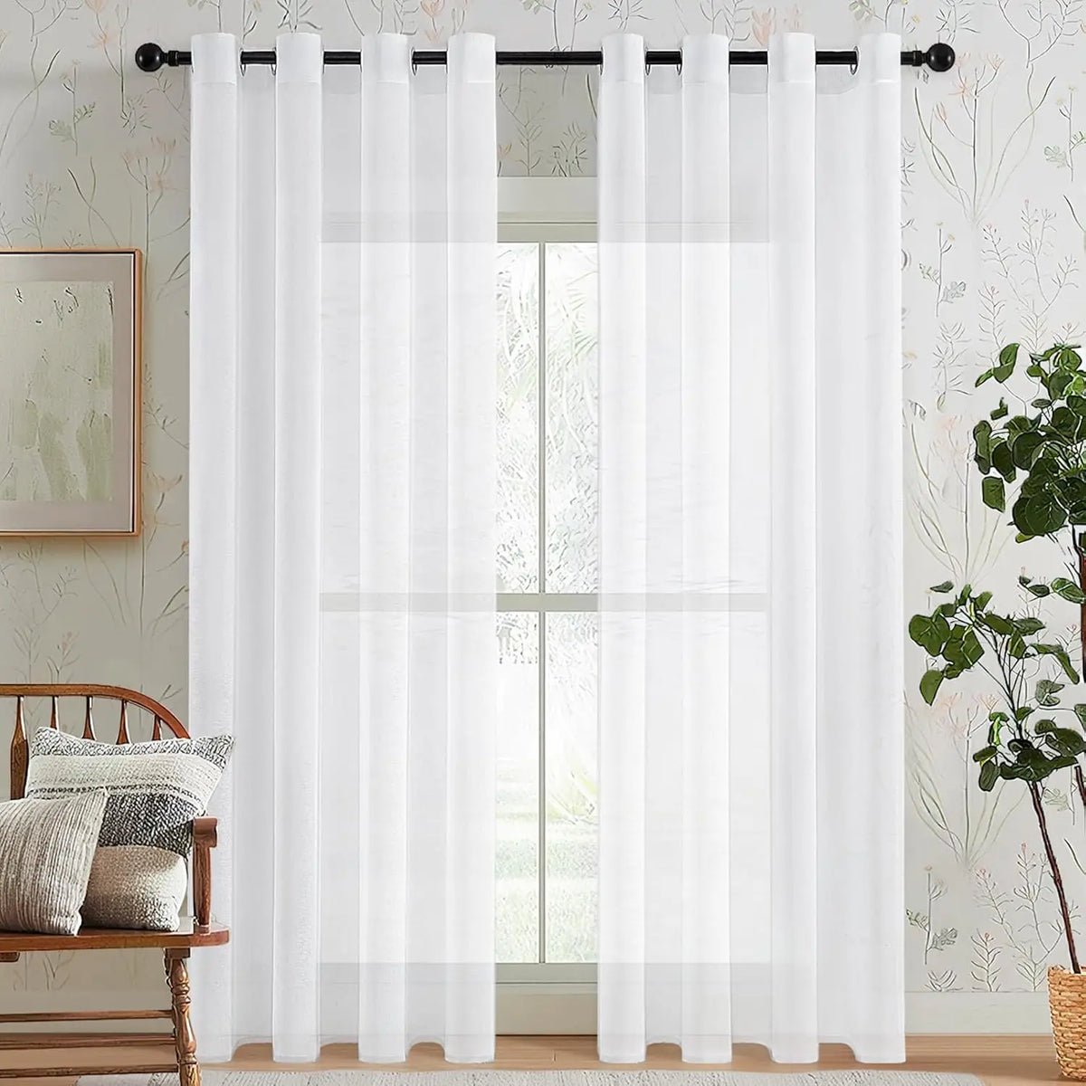 White sheer tulle window curtains hanging in a window with a light floral wallpaper background