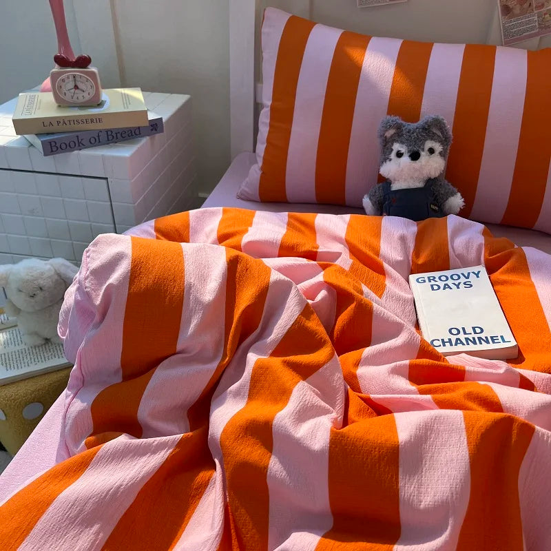 A pink and orange striped duvet cover set with a stuffed animal resting on the bedding.
