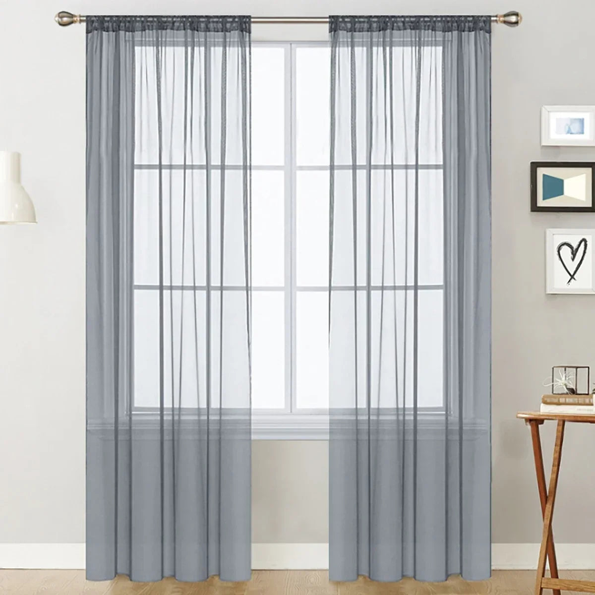 Gray sheer curtain panels with a rod pocket hanging in front of a white window.
