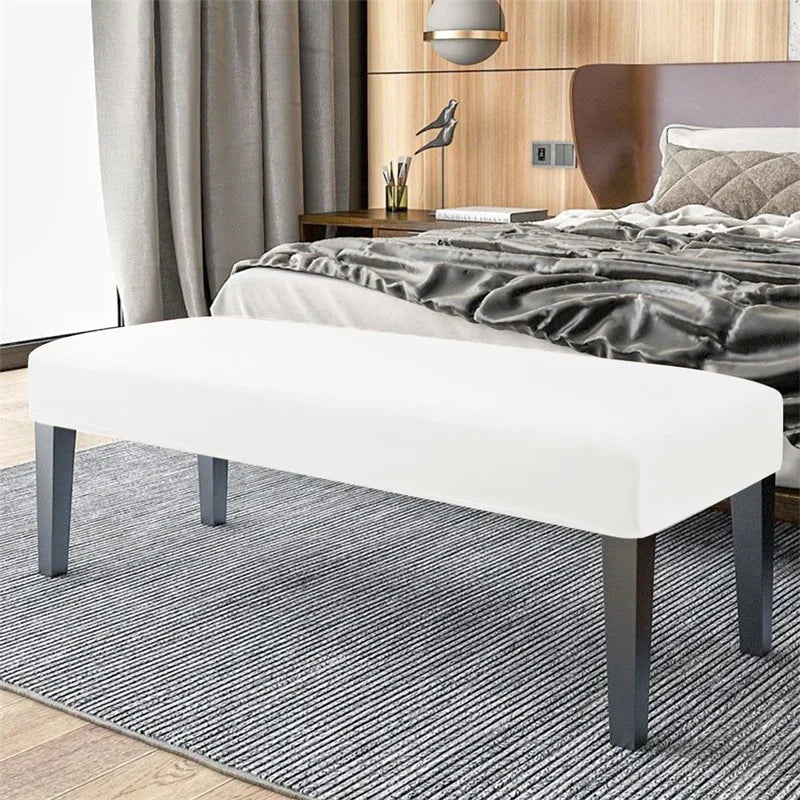 A white bench with dark legs and a gray striped rug placed in front of a wooden bed.