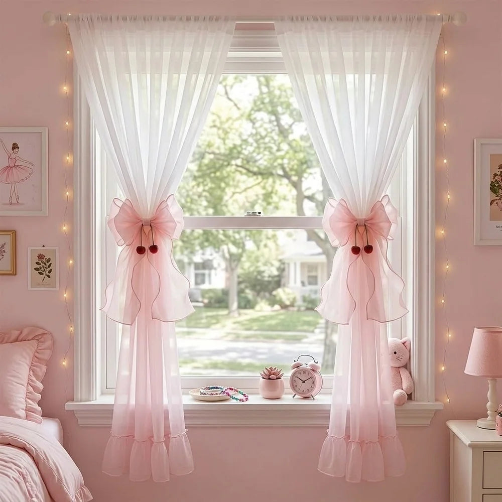 A window decorated with pink sheer curtains tied back in French ribbon bows, featuring a light pink bedroom setting.