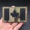 A tactical patch featuring a black rectangle and a Canadian maple leaf on a camouflage background.