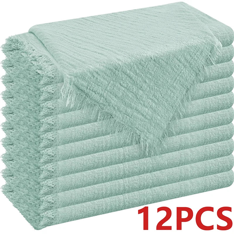 A stack of light mint green decorative cloth napkins with fringed edges.