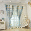 Light blue sheer floral curtains with lace trim hanging in a window