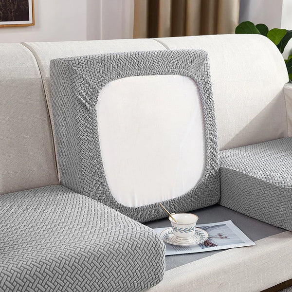 A gray woven fabric sofa seat cushion cover with a white insert shown on a light-colored sofa.