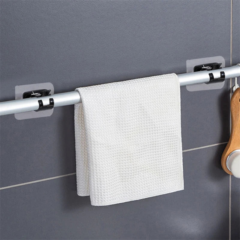 A white textured towel is hanging on a silver curtain rod with black brackets against a gray tiled wall.