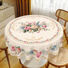 A round table covered with a vintage pink rose sunflower floral tablecloth, set in a bright room.