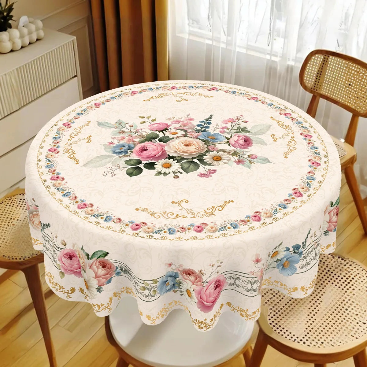 A round table covered with a vintage pink rose sunflower floral tablecloth, set in a bright room.