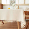 A cream textured cotton tassel table runner displayed on a wooden table.