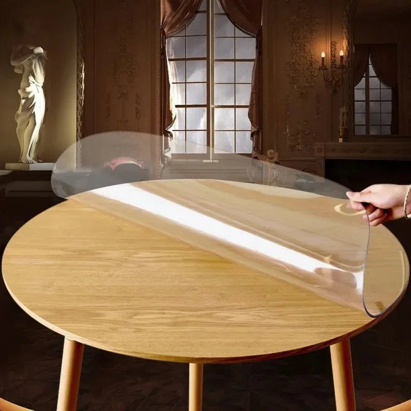 A round, light wood table with a clear plastic protective sheet placed on top.