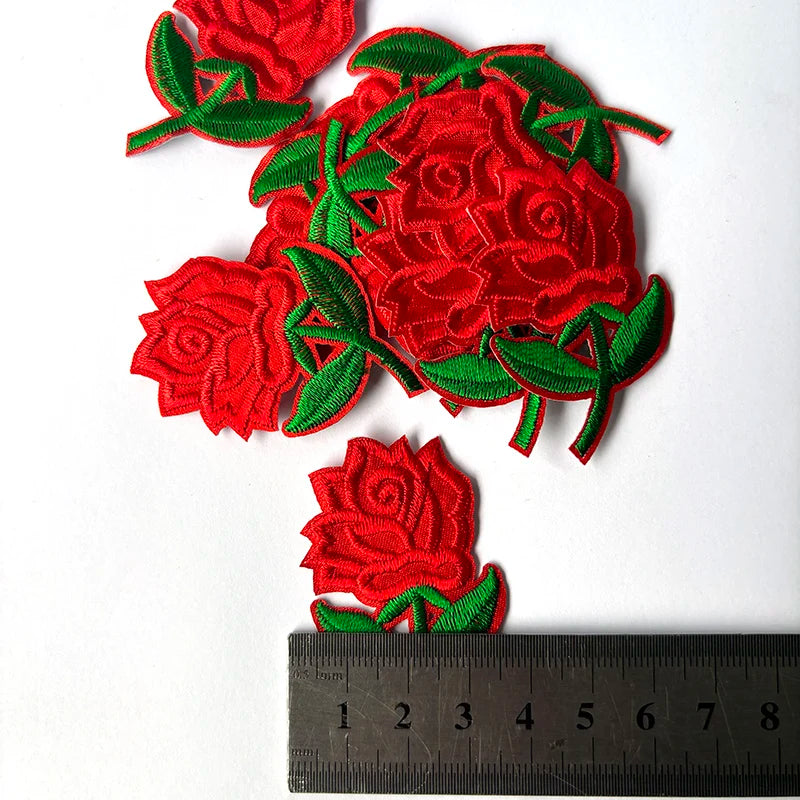 Red embroidered rose flower patches with green leaves on a white background