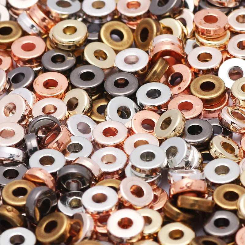 A close-up view of small, round acrylic flat spacer beads in various gold and silver tones.