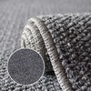 A close-up of a thick, textured gray sisal jute rug folded on a surface.