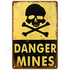 A vintage metal wall art sign with a black skull and crossbones symbol and the text DANGER MINES on a yellow background.