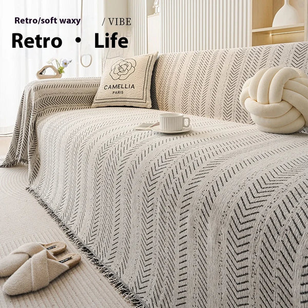 A beige textured sofa cover featuring a geometric fishbone pattern and cream accent pillows.