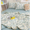 A light blue summer gauze cotton quilt with a floral pattern and a small stuffed animal on a bed.