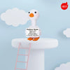 A white goose plush toy with orange beak and feet sitting on a white pedestal.