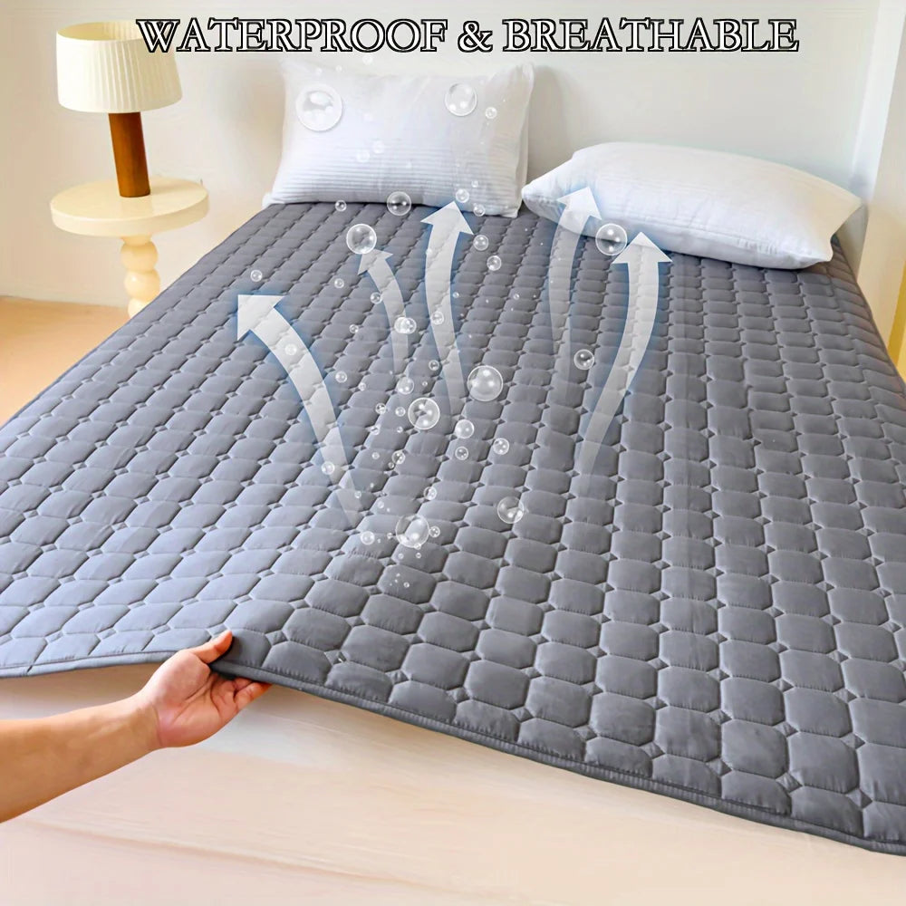 A gray quilted waterproof mattress protector is shown on a bed, demonstrating its breathable features.