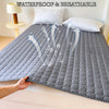 Gray quilted waterproof mattress protector cover shown on a bed with arrows indicating breathability.