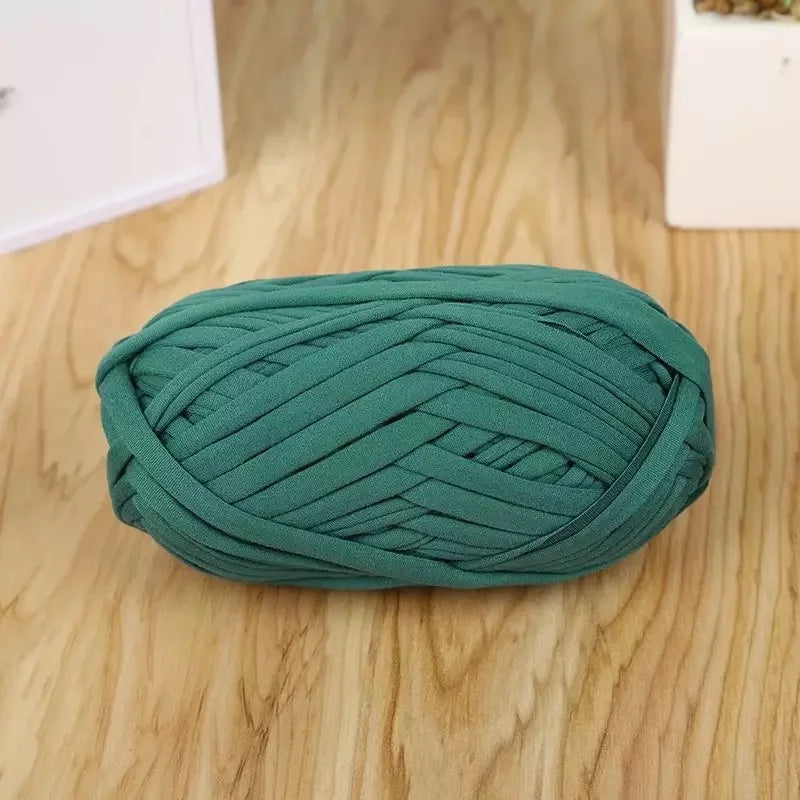 A ball of teal green flat thread yarn for crafting and sewing lying on a wooden surface.