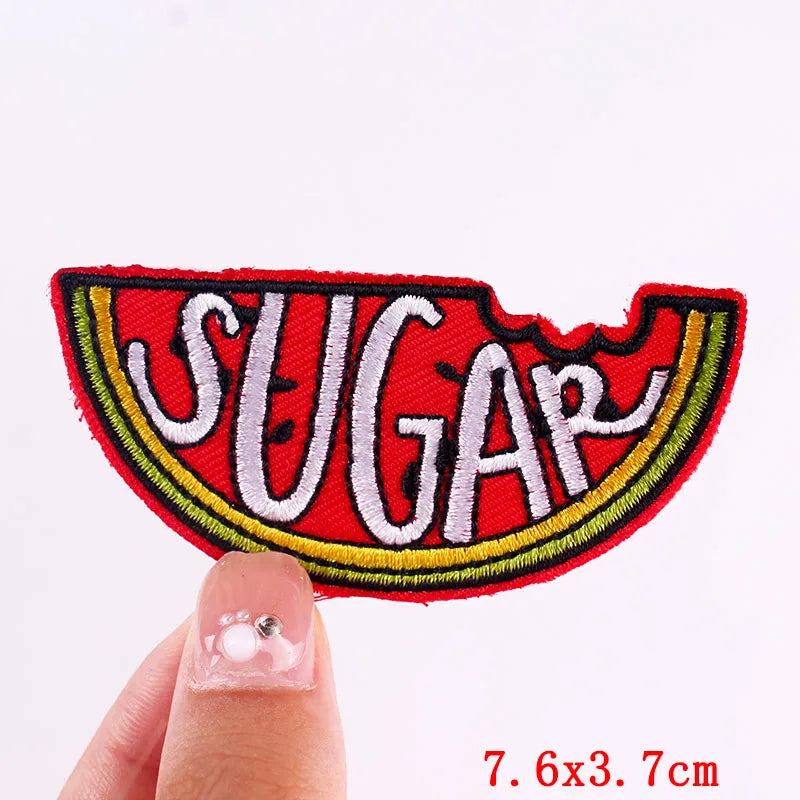 Red embroidered letter patch spelling SUGAR on a finger