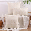 A stack of cream embroidered throw pillows featuring a geometric maze pattern on a light wood floor.