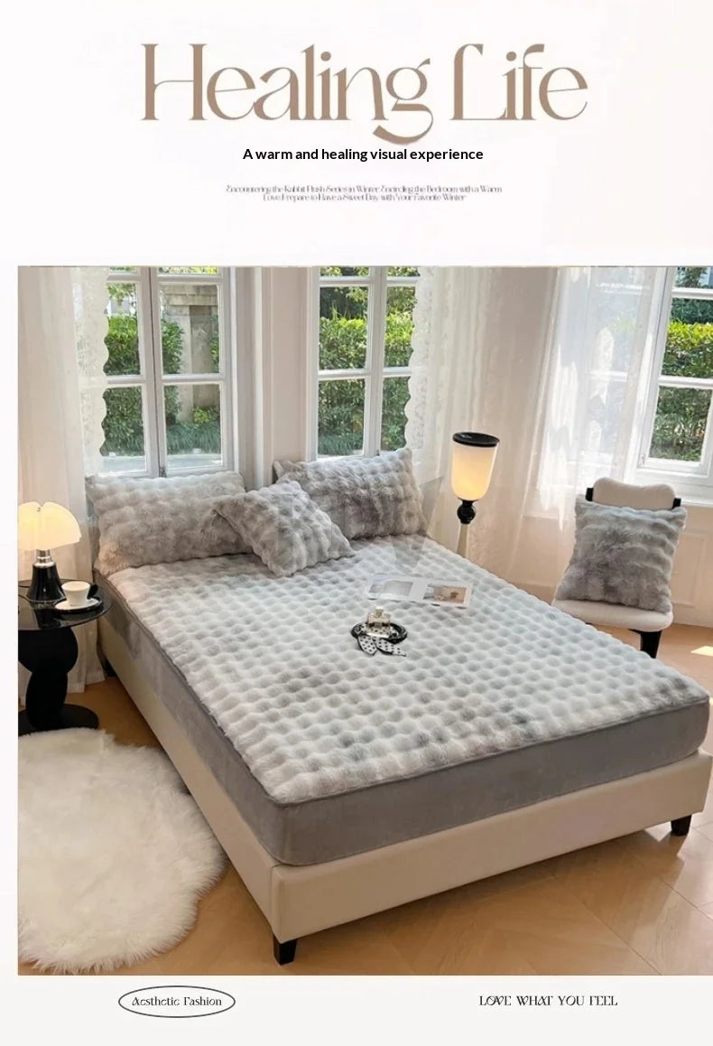 A luxury faux rabbit fur fitted sheet set displayed on a bed with white curtains and natural light.