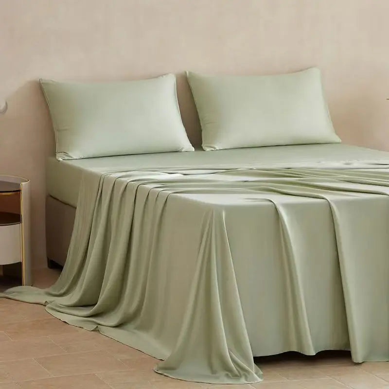 A light sage green bamboo fiber flat bed sheet draped over a bed, showing its smooth texture.