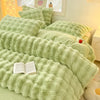 A plush rabbit hair bedding set in light green featuring various textured pillows and a green duvet.