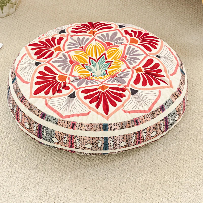 A round bohemian tatami cushion featuring a vibrant floral pattern in red, orange, yellow, and purple on a cream background.