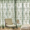 Sheer floral lace curtain panels in green and white hanging in a window.