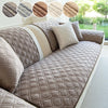 A beige quilted sofa cushion cover with a neutral tone and white trim, shown on a sofa.