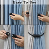 A set of magnetic curtain tiebacks in black and silver are shown being used to hold a blue and gray fabric curtain.