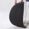 A hand is holding a black half-round non-slip PVC door mat with a diamond pattern.