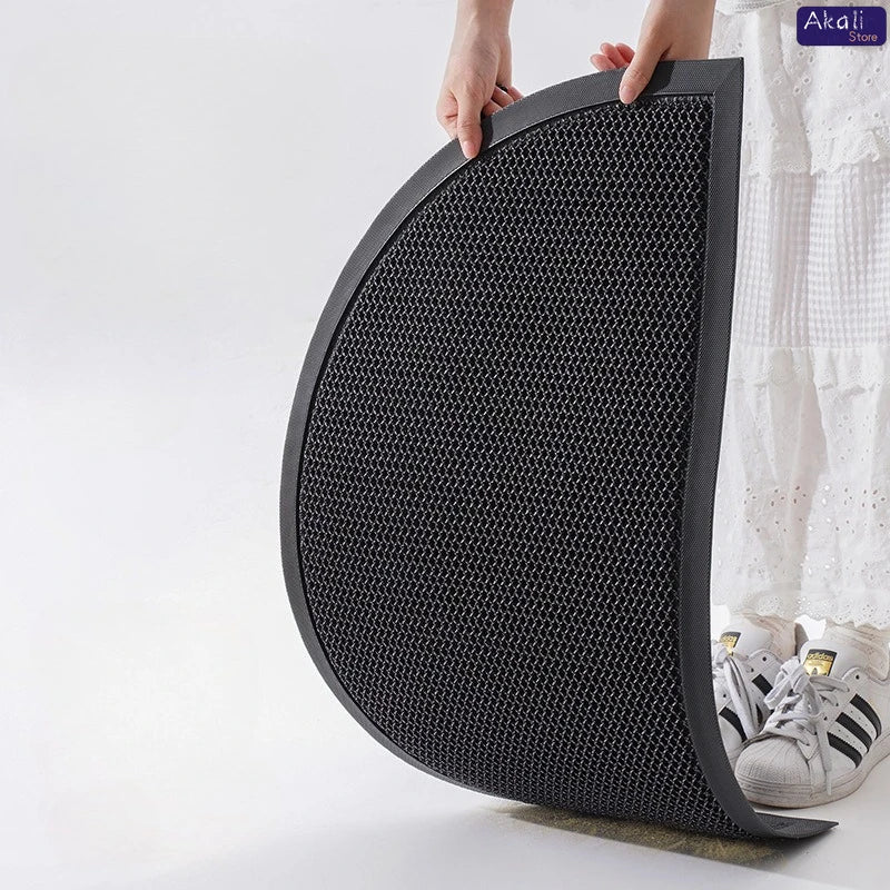A hand is holding a black half-round non-slip PVC door mat with a diamond pattern.