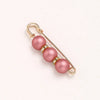 A delicate gold-toned adjustable pearl brooch featuring three round pink pearls.