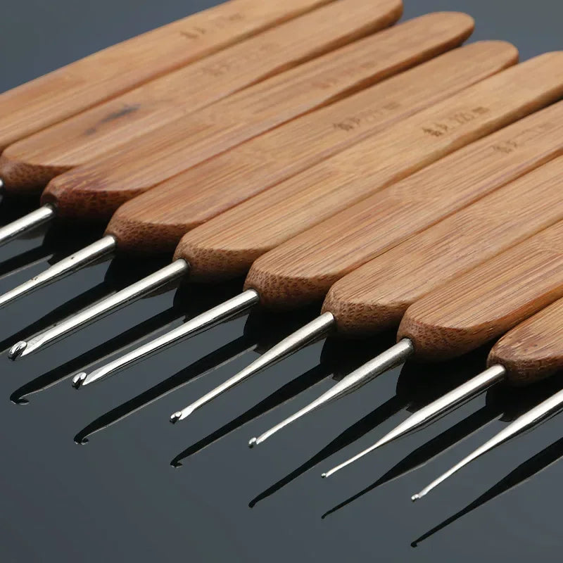 A set of light brown bamboo crochet knitting needles arranged diagonally on a dark surface.