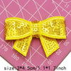 Yellow sequin bow patches for DIY decoration shown on a pink grid background
