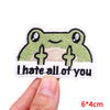 An embroidered patch featuring a smiling green frog with the text I hate all of you.