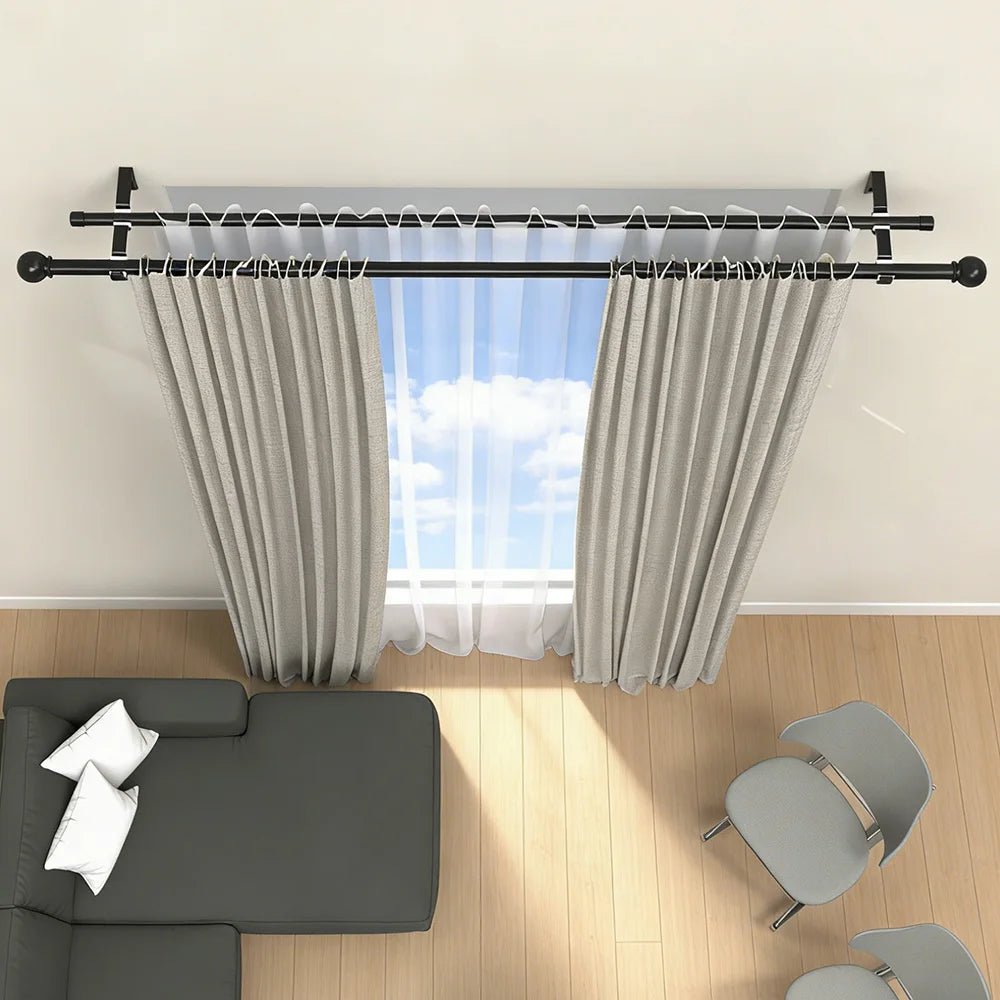 Black metal adjustable double curtain rod set with sheer white curtains in a bright room.