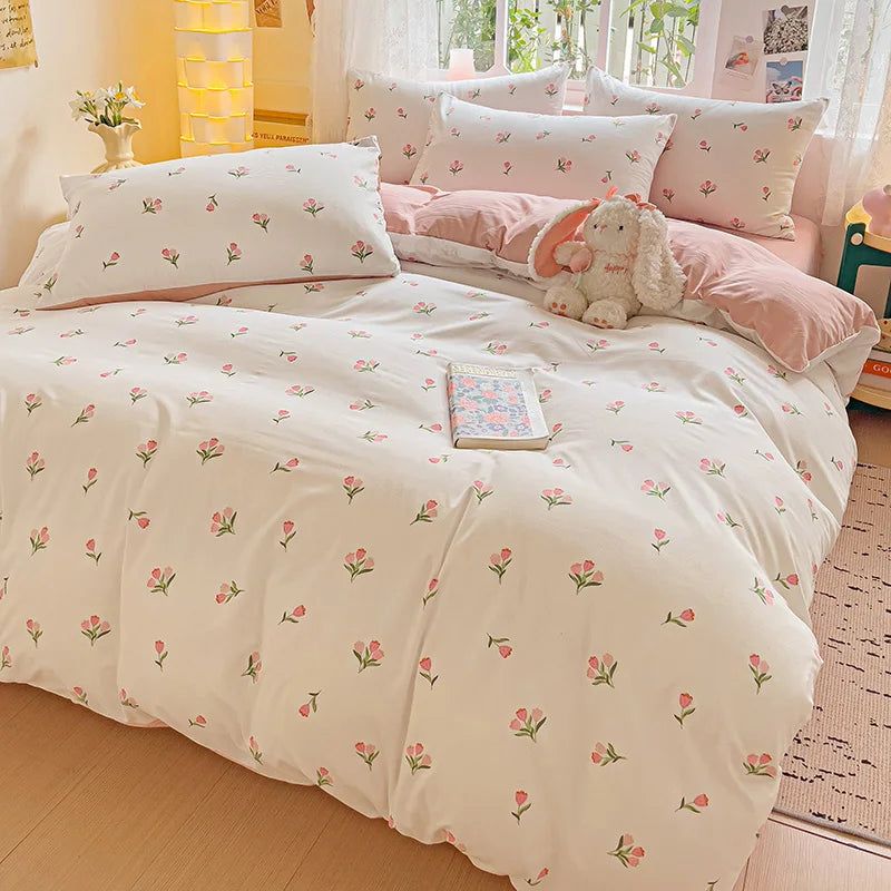 A pink floral printed bedding set featuring white sheets and pillows with a stuffed rabbit toy.