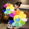 A young woman holds a large, colorful sunflower plush cushion with a smiling face, demonstrating its size.