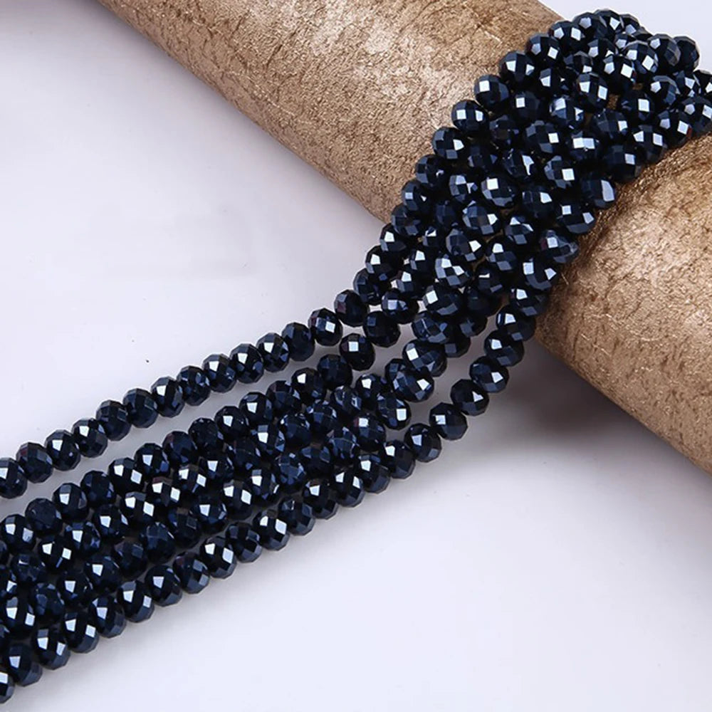 A strand of dark blue faceted rondelle glass beads is shown coiled on a natural fiber material.